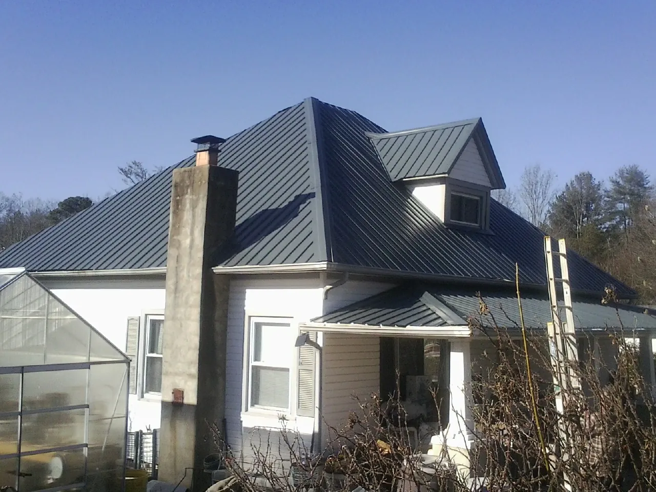 Dark blue standing seam metal roof on a white farmhouse with dormer — Slate & Tile Roof Repair by Roofing Brothers in Allston