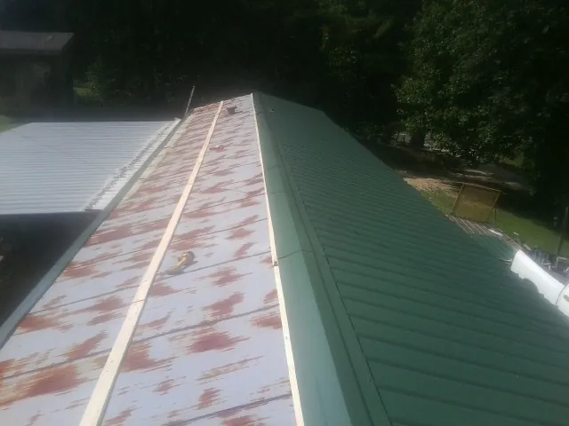 Old rusted panels beside newly installed green metal roofing — Wind Damage Roof Repair by Roofing Brothers in Allston