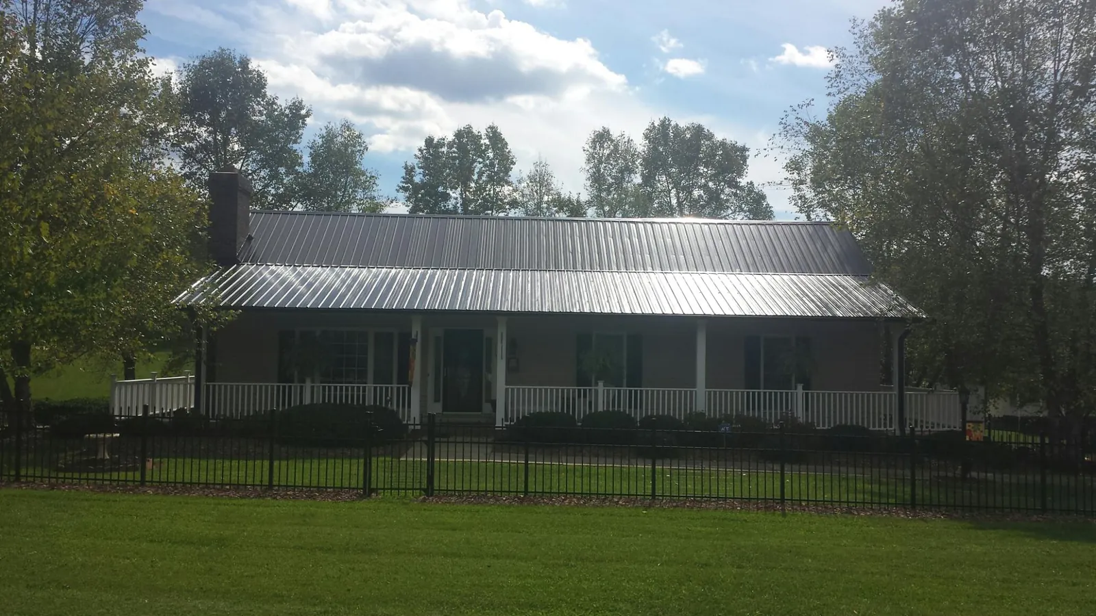 Gray metal roof on a brick ranch with a full width front porch — Gutter Guard Installation work by our crew in Allston